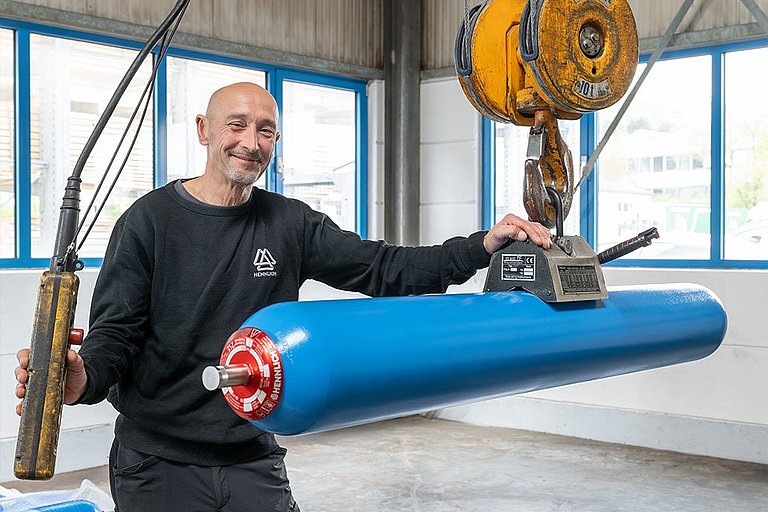 Dirk Fuhrmann steht neben einem langen Blasenspeicher, der an einem Elektrokettenzug hängt