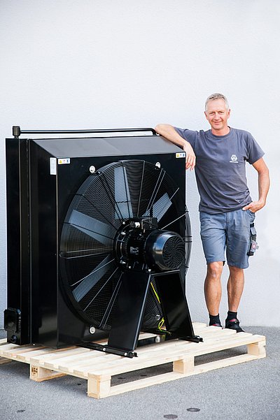 Mitarbeiter Robert Boxrucker neben einem großen Luftkühler