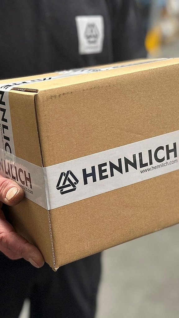 Person hält ein Paket mit Hennlich Packband