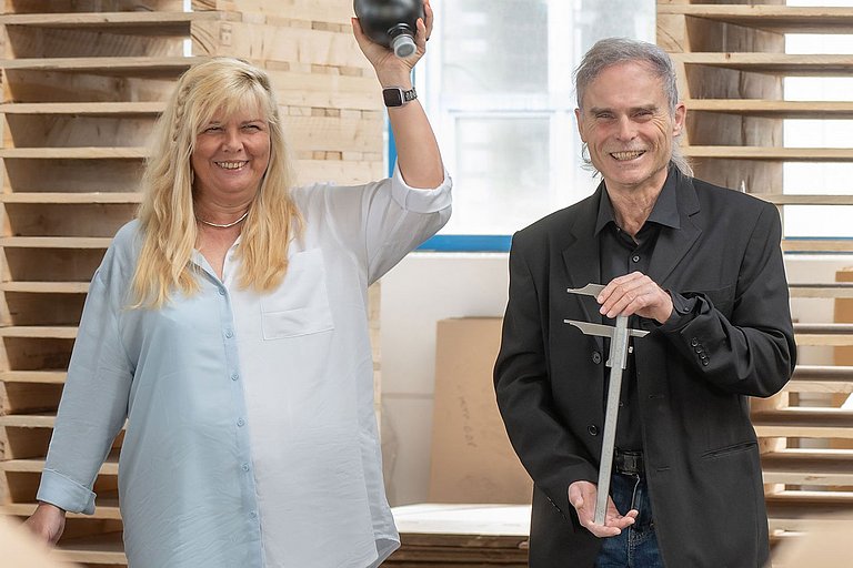 Drei Mitarbeiter schauen in die Kamera und halten eine Konsole, einen Membranspeicher und einen Messschieber